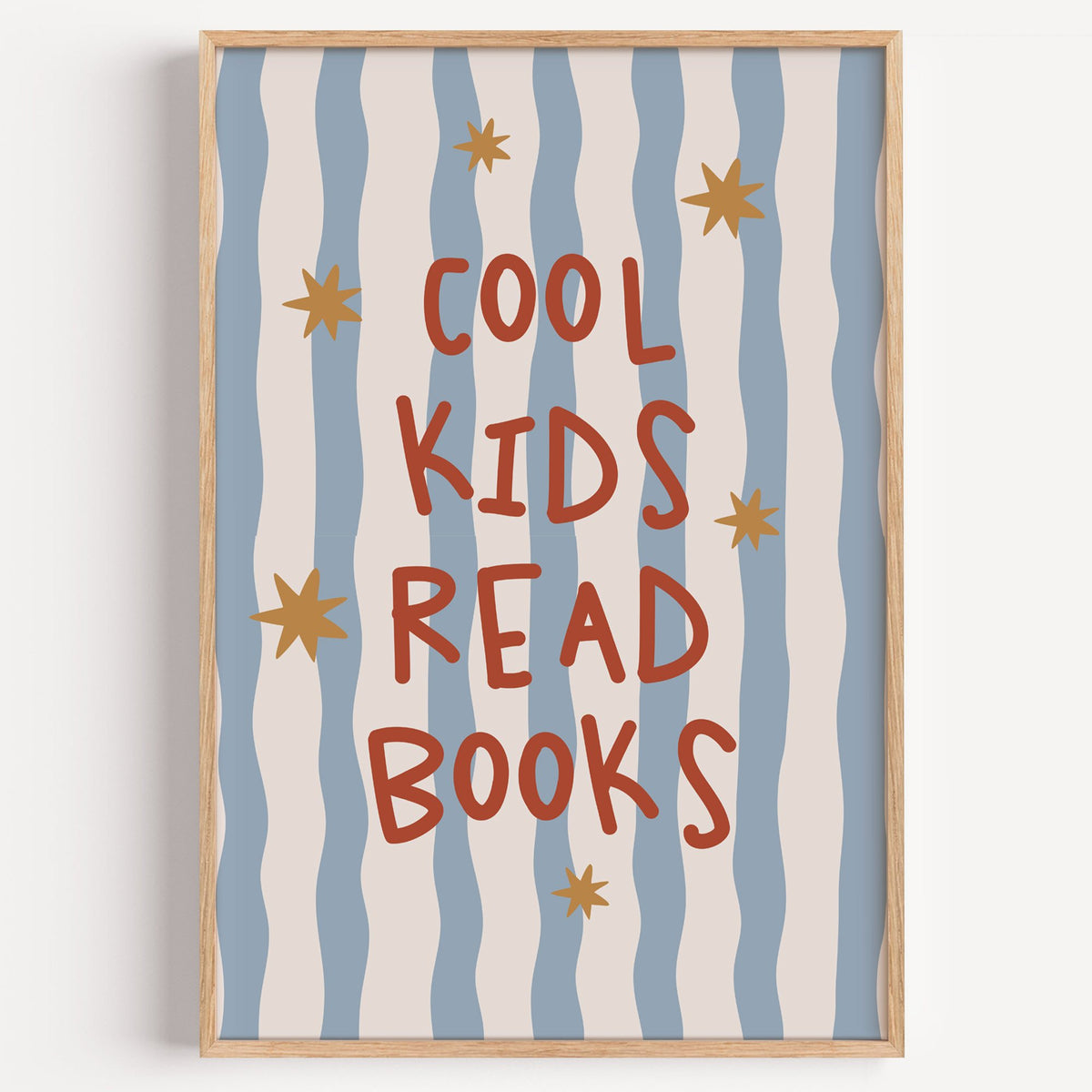 Cool kids read books gold stars nursery print in a light oak frame on a plain white wall