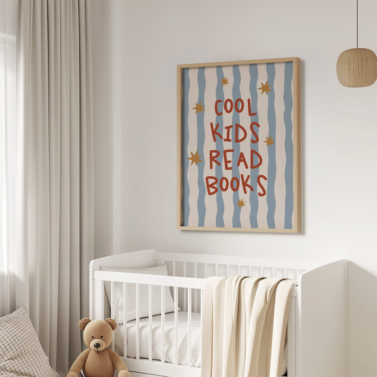 Cool kids read books gold stars nursery print in an oak frame above a white crib with a teddy bear