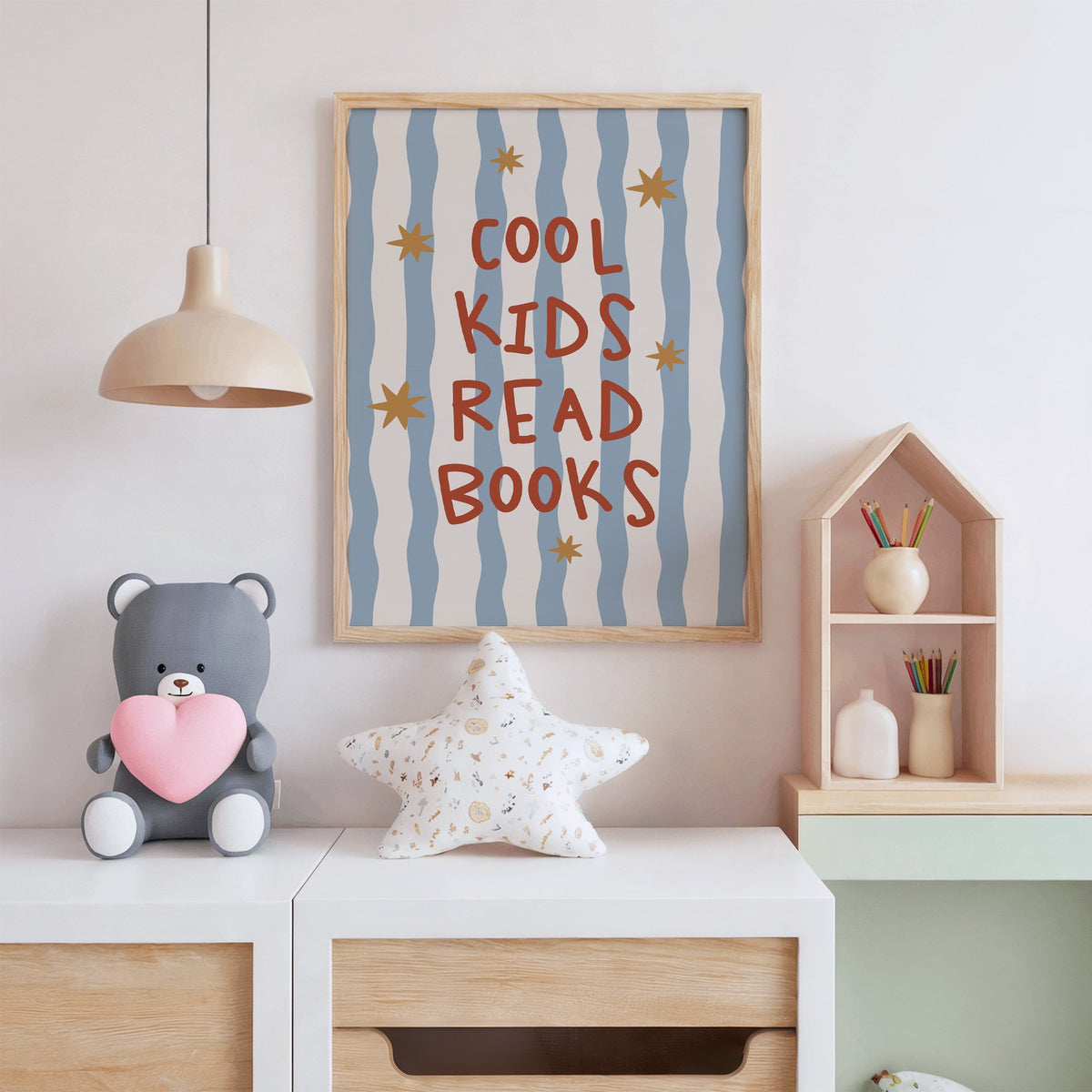 Cool kids read books gold stars nursery print in an oak frame above a white dresser with a star pillow and house shelf
