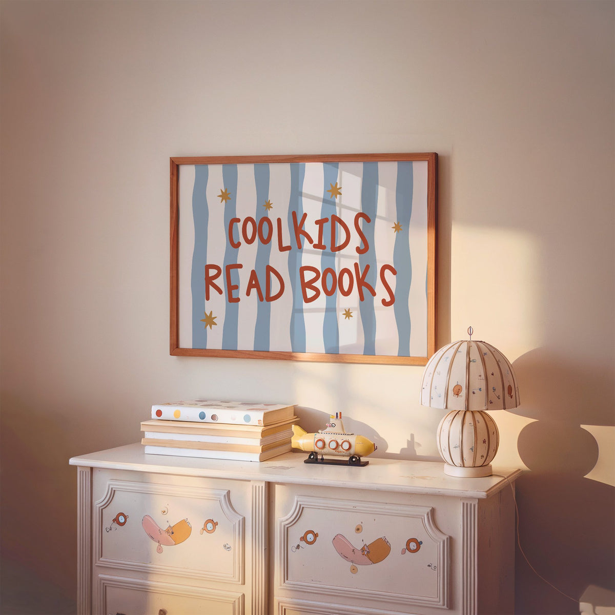 Landscape cool kids read books gold stars nursery print in a cherry wood frame above a painted dresser and lamp