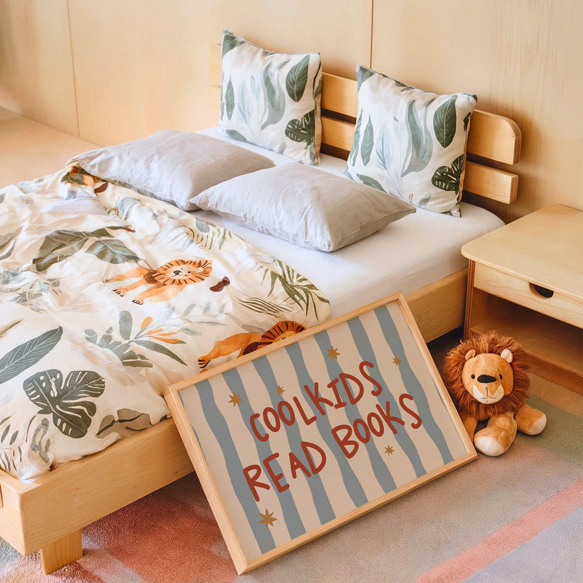 Landscape cool kids read books gold stars nursery print in an oak frame leaning on a kids bed by a lion plush