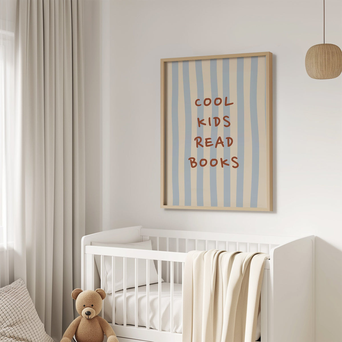 Cool kids read books blue stripe nursery print in an oak frame above a white crib with a teddy bear