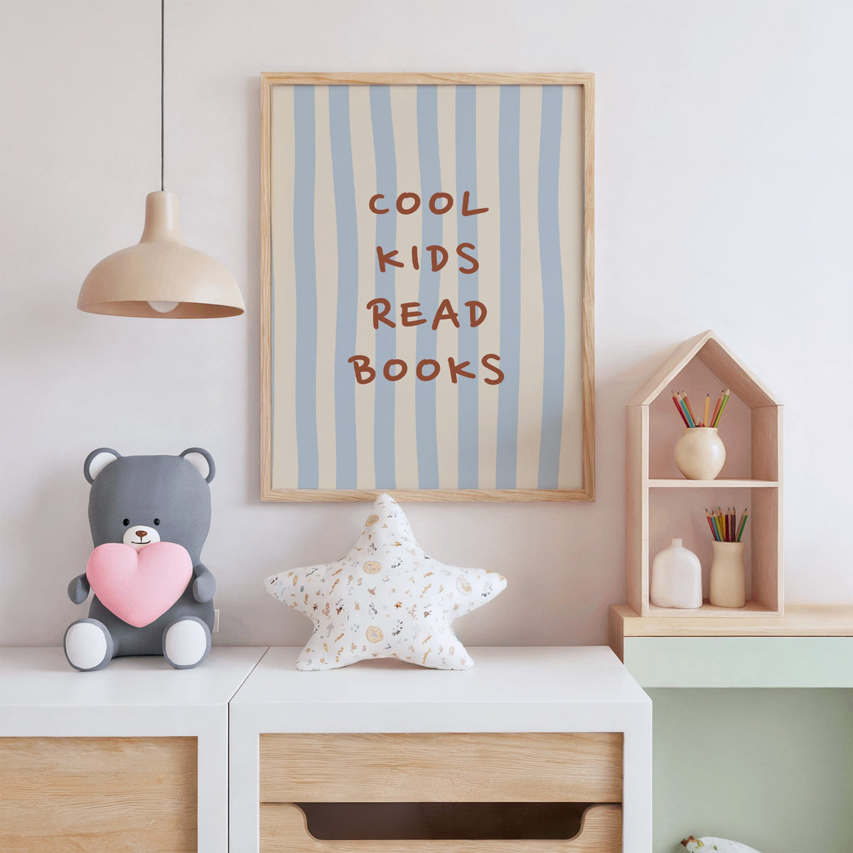 Cool kids read books blue stripe nursery print in an oak frame above a white dresser with a star pillow and house shelf