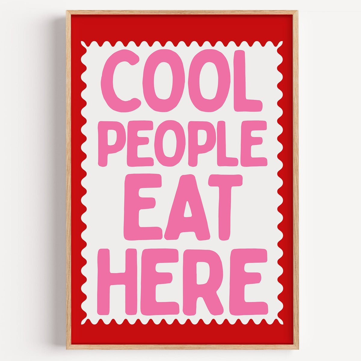 Cool People Eat Here print in a light oak frame on a plain white wall