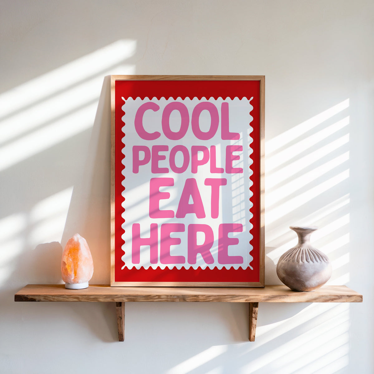 Cool People Eat Here print in an oak frame on a live-edge shelf beside a salt lamp