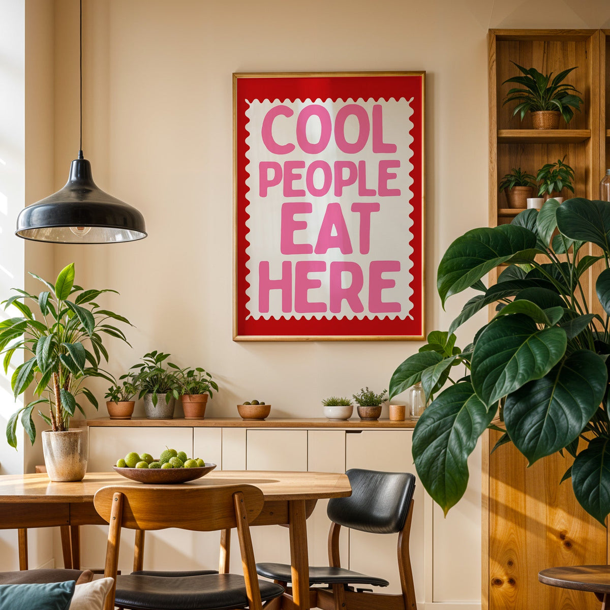 Cool People Eat Here print in an oak frame in a dining room above a plant-lined sideboard