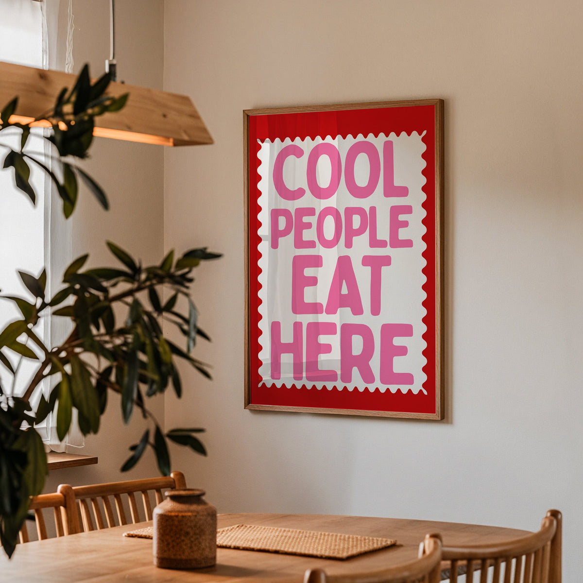 Cool People Eat Here print in a walnut frame above a dining table with olive branches
