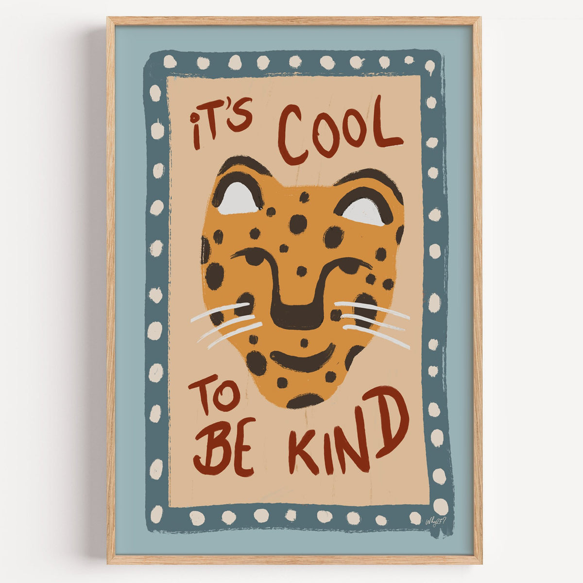 Cool to be kind cat quote nursery print in a light oak frame on a plain white wall