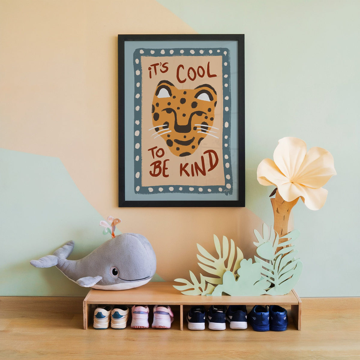 Cool to be kind cat quote nursery print in a black frame on a mint and peach wall above a whale plush