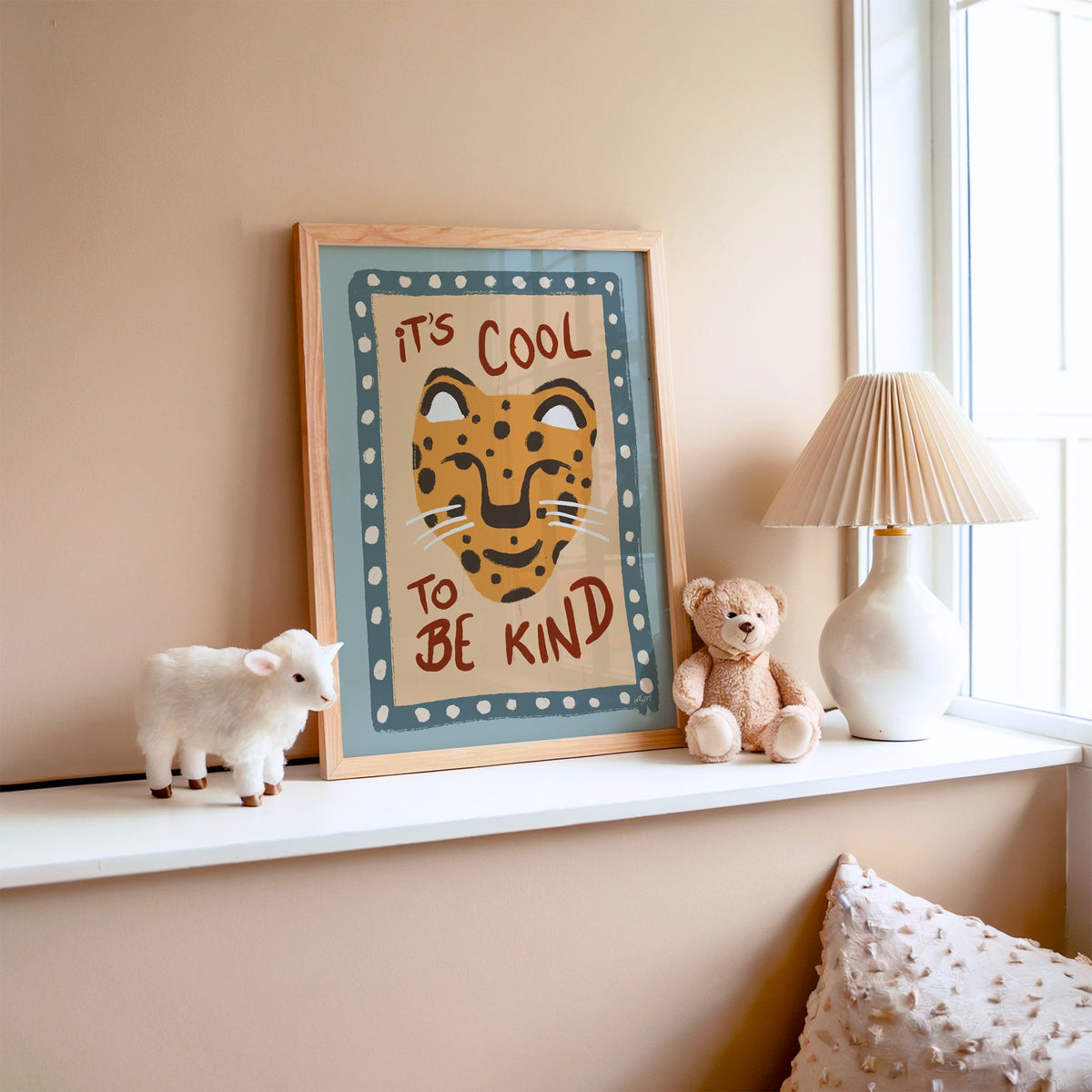 Cool to be kind cat quote nursery print in an oak frame on a window ledge with a toy lamb and teddy