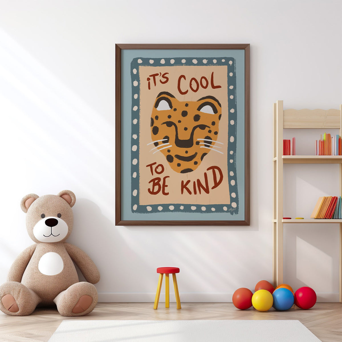 Cool to be kind cat quote nursery print in a walnut frame above a big teddy bear by a bookshelf