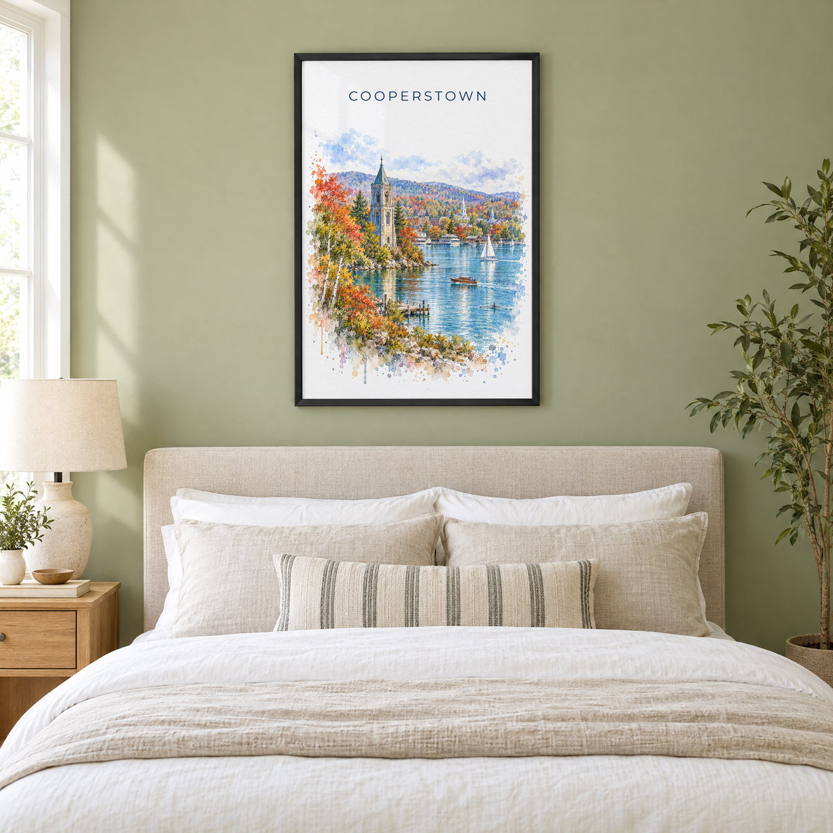 Cooperstown watercolor print in a black frame above an upholstered headboard in a sage green bedroom