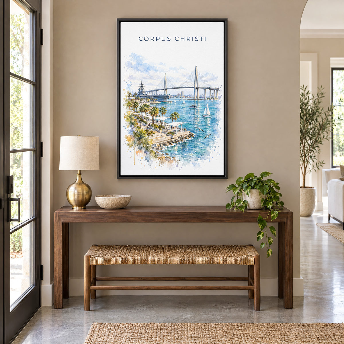 Corpus Christi watercolor print as a black floater canvas above a walnut console and woven bench in an entryway