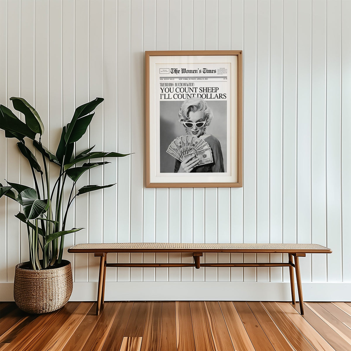 Woman fanning dollar bills mock front page print in a wood frame with a white mat above a cane bench