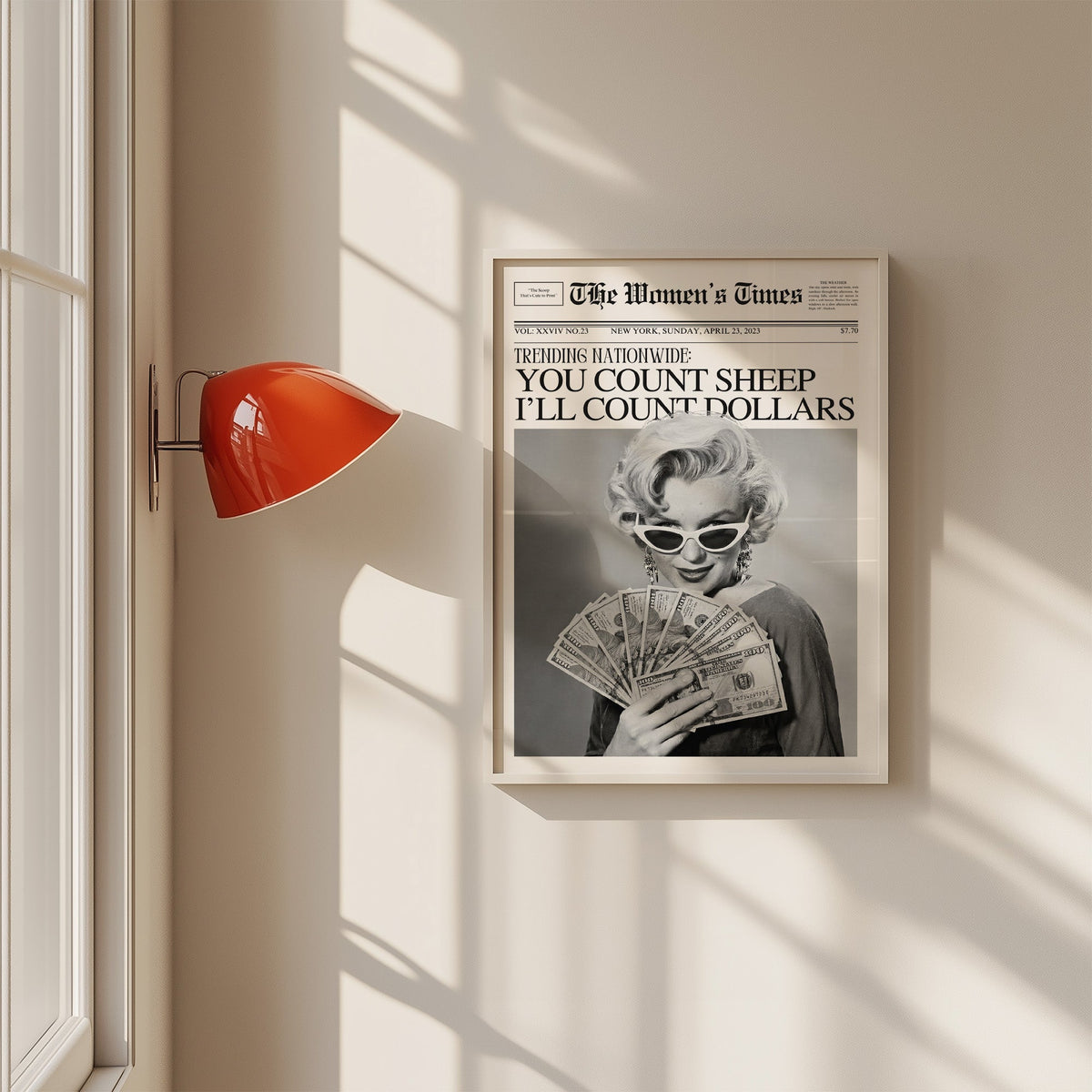 Woman fanning dollar bills mock front page print in a white frame on a sunlit wall beside a red sconce