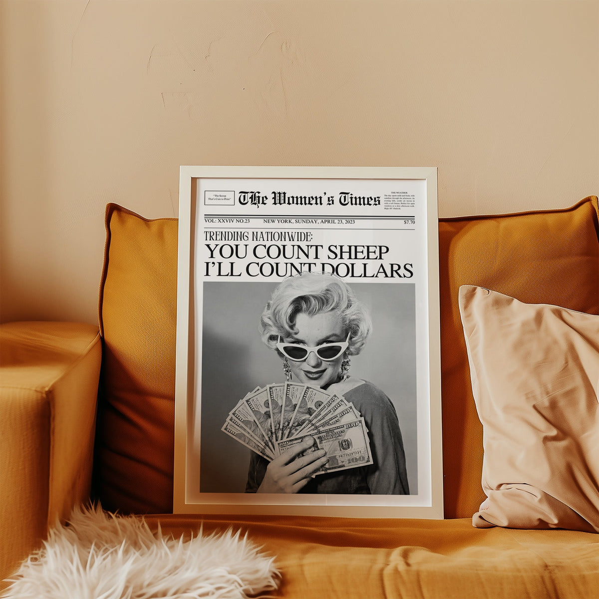 Woman fanning dollar bills mock front page print in a white frame leaning on a mustard velvet sofa