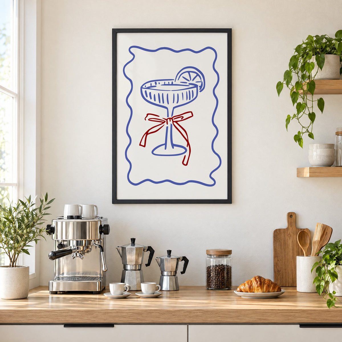 Blue coupe glass with red bow print in a black frame above a home espresso bar with moka pots and espresso cups