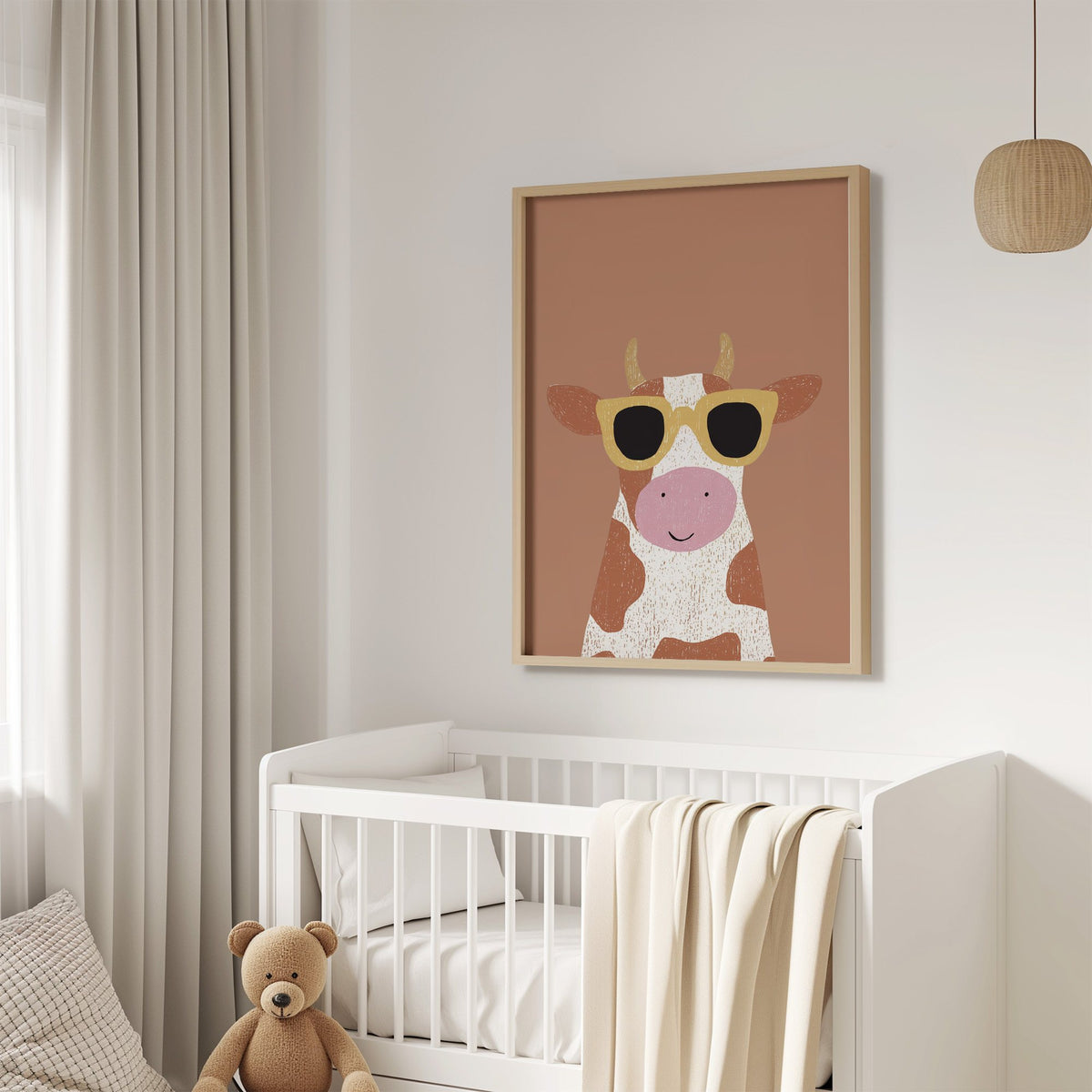 Cow in yellow sunglasses nursery print in an oak frame above a white crib with a teddy bear