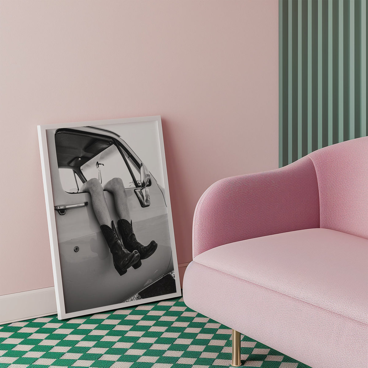 Cowboy boots dangling from a truck window print in a white frame beside a pink armchair on a checkered floor