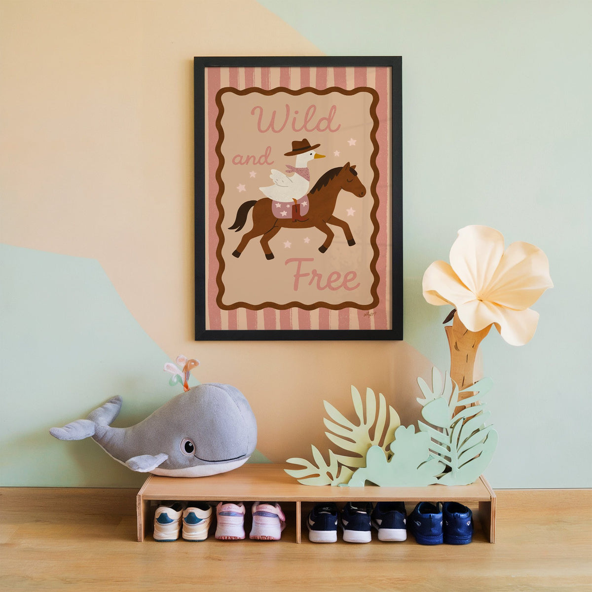 Cowboy goose riding a brown horse nursery print in a black frame on a mint and peach wall above a whale plush