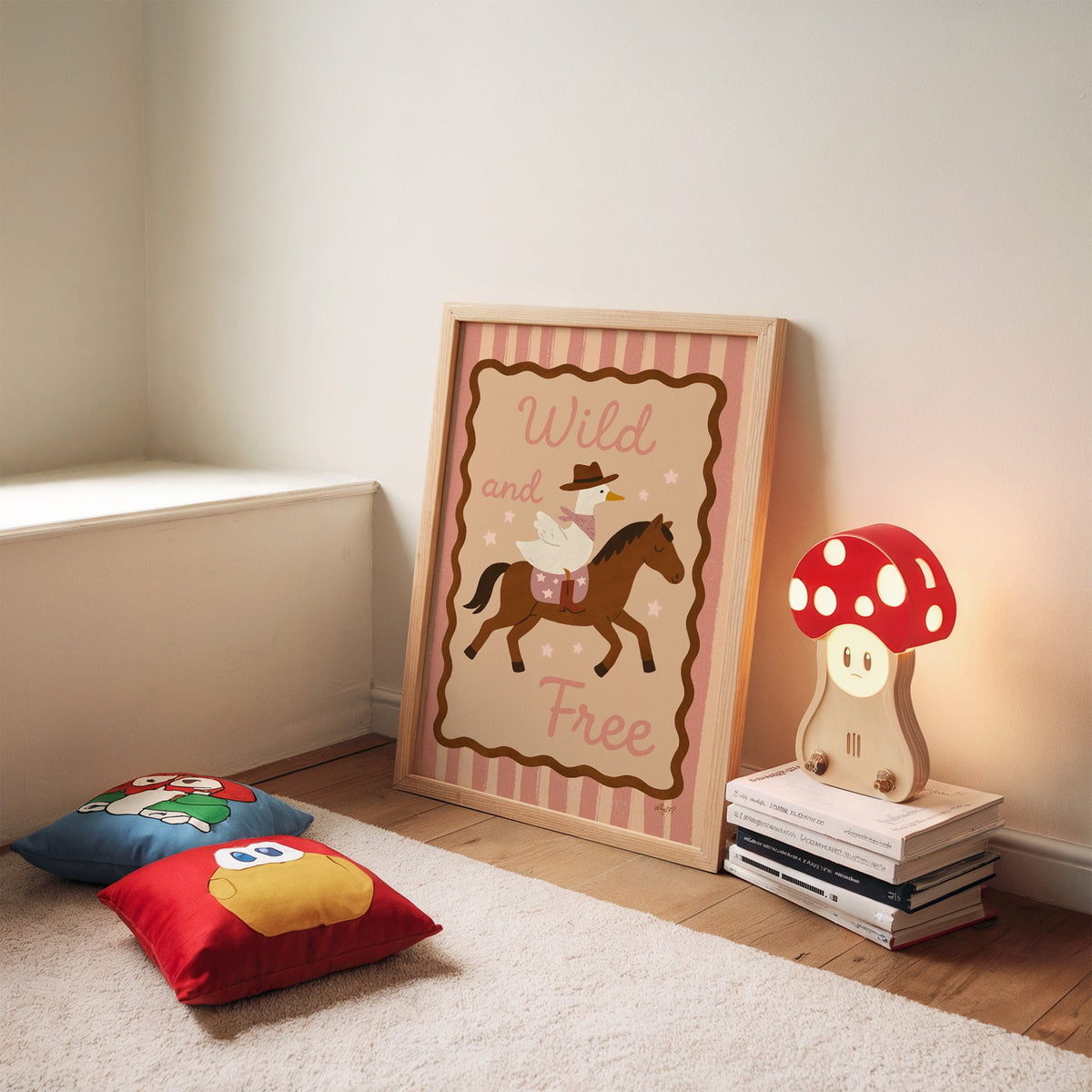 Cowboy goose riding a brown horse nursery print in an oak frame leaning on a rug beside a mushroom lamp and floor cushions
