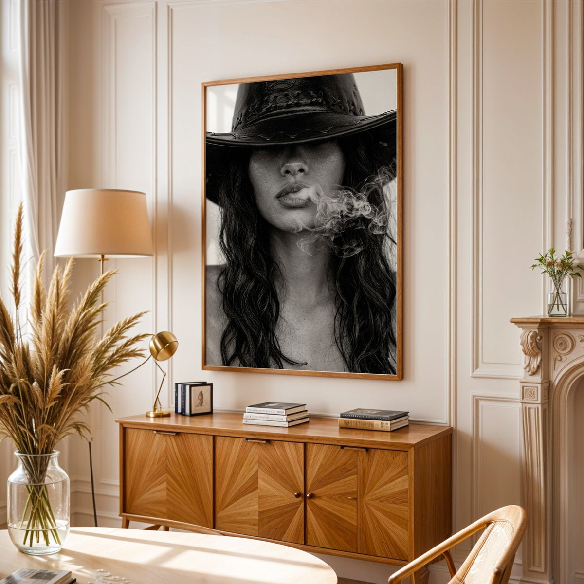 Cowboy hat brim and smoke from lips closeup print in an oak frame above a sunburst wood sideboard with pampas grass