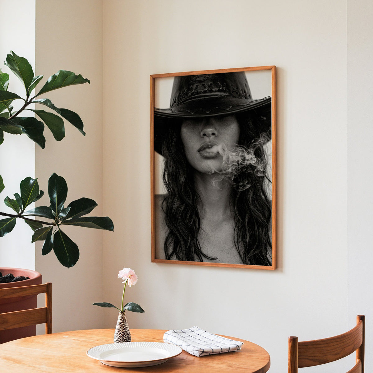 Cowboy hat brim and smoke from lips closeup print in a teak frame above a round wooden dining table