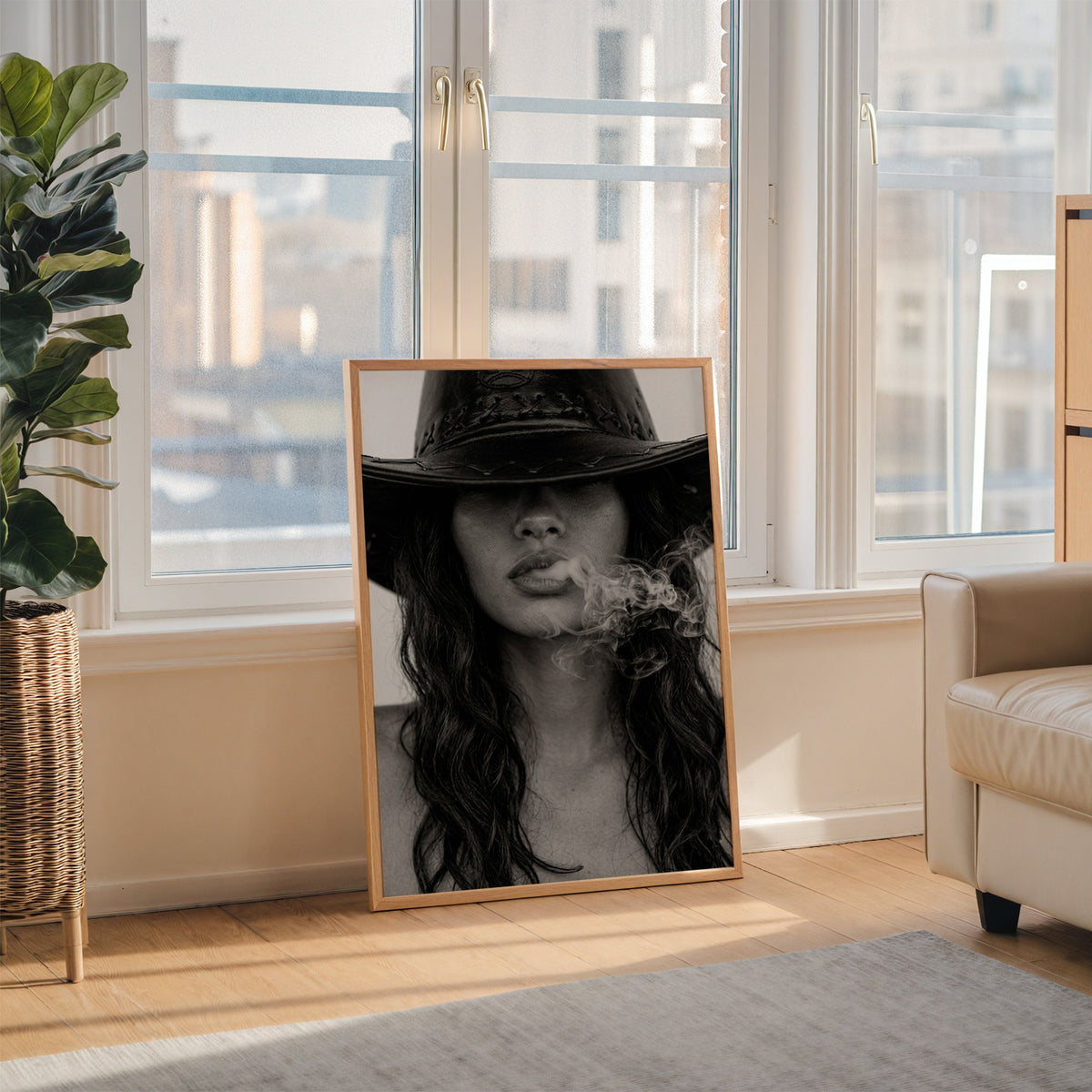 Cowboy hat brim and smoke from lips closeup print in an oak frame leaning on the floor beside a fiddle leaf fig