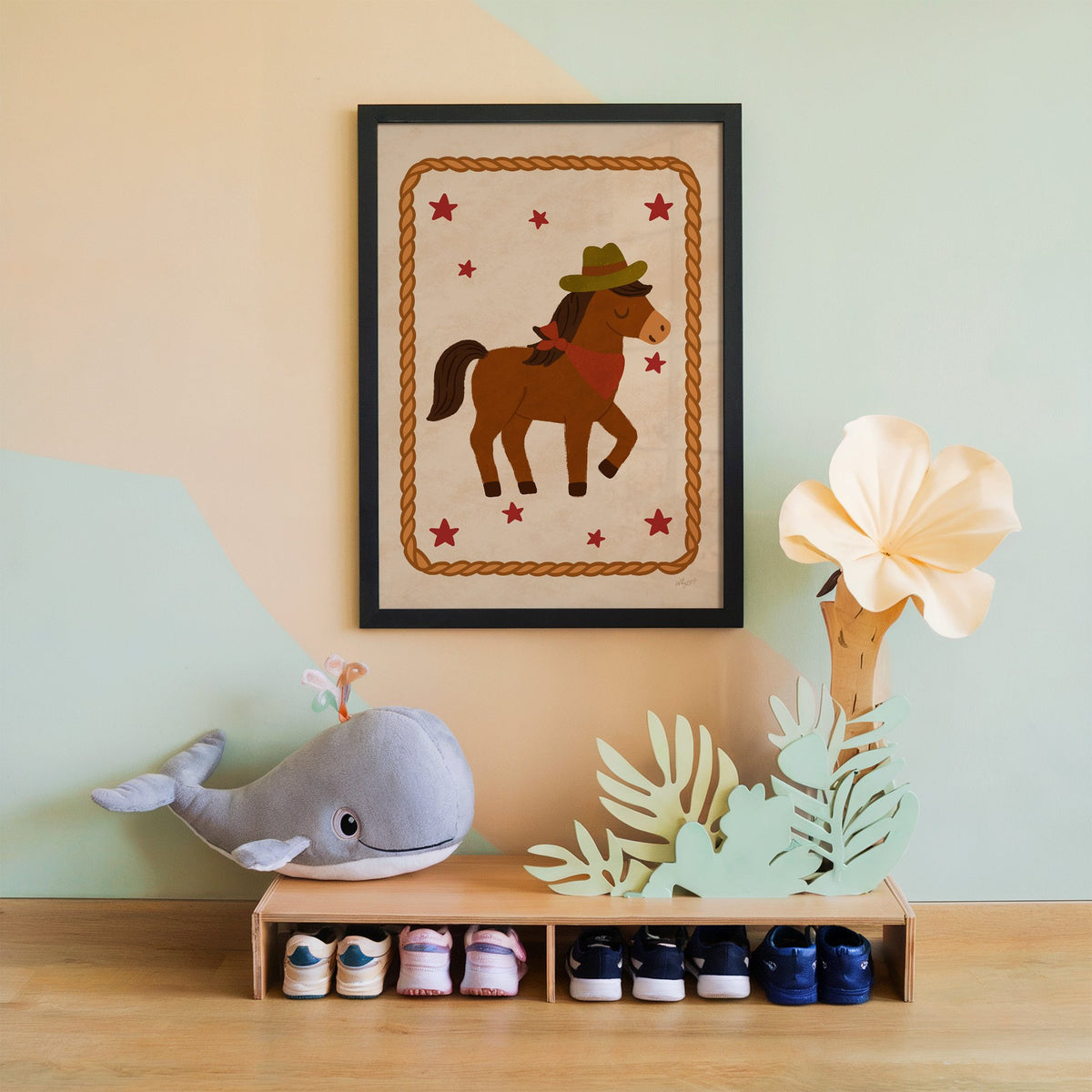 Cowboy pony in rope frame nursery print in a black frame on a mint and peach wall above a whale plush