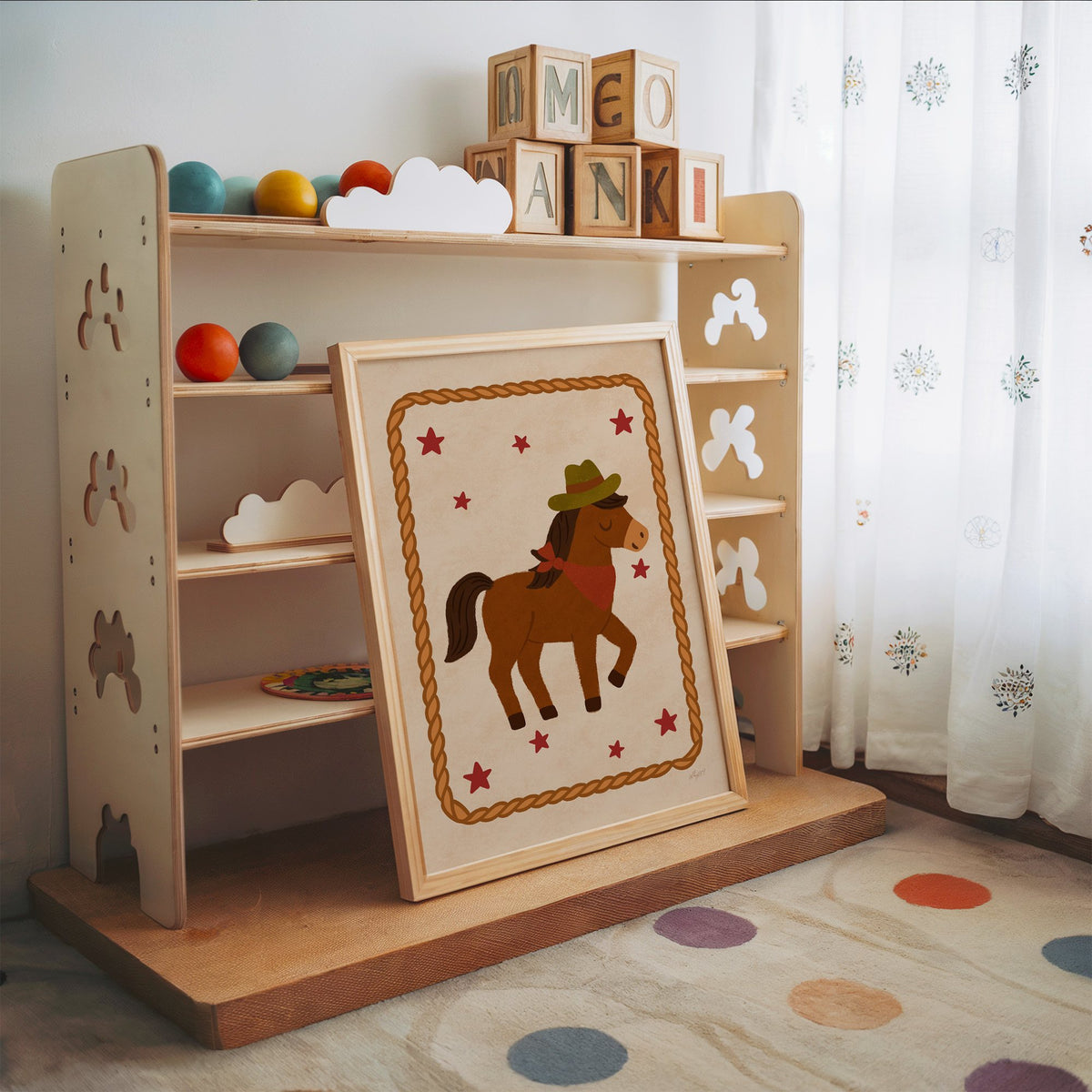 Cowboy pony in rope frame nursery print in an oak frame leaning on a toy shelf with wooden letter blocks