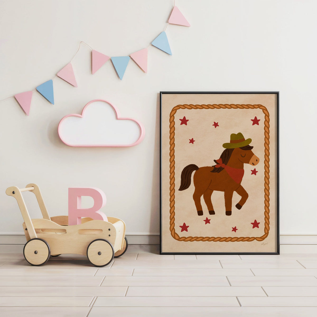 Cowboy pony in rope frame nursery print in a black frame under pastel bunting by a wooden baby walker