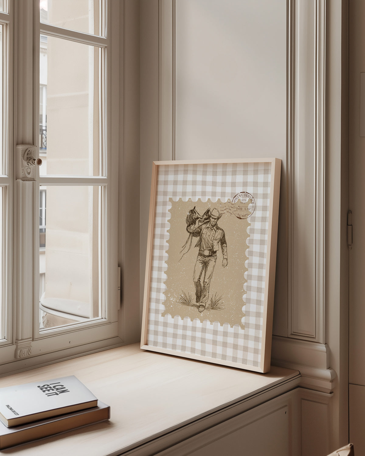 Cowboy saddle gingham print in a pale wood frame on a sunlit window ledge