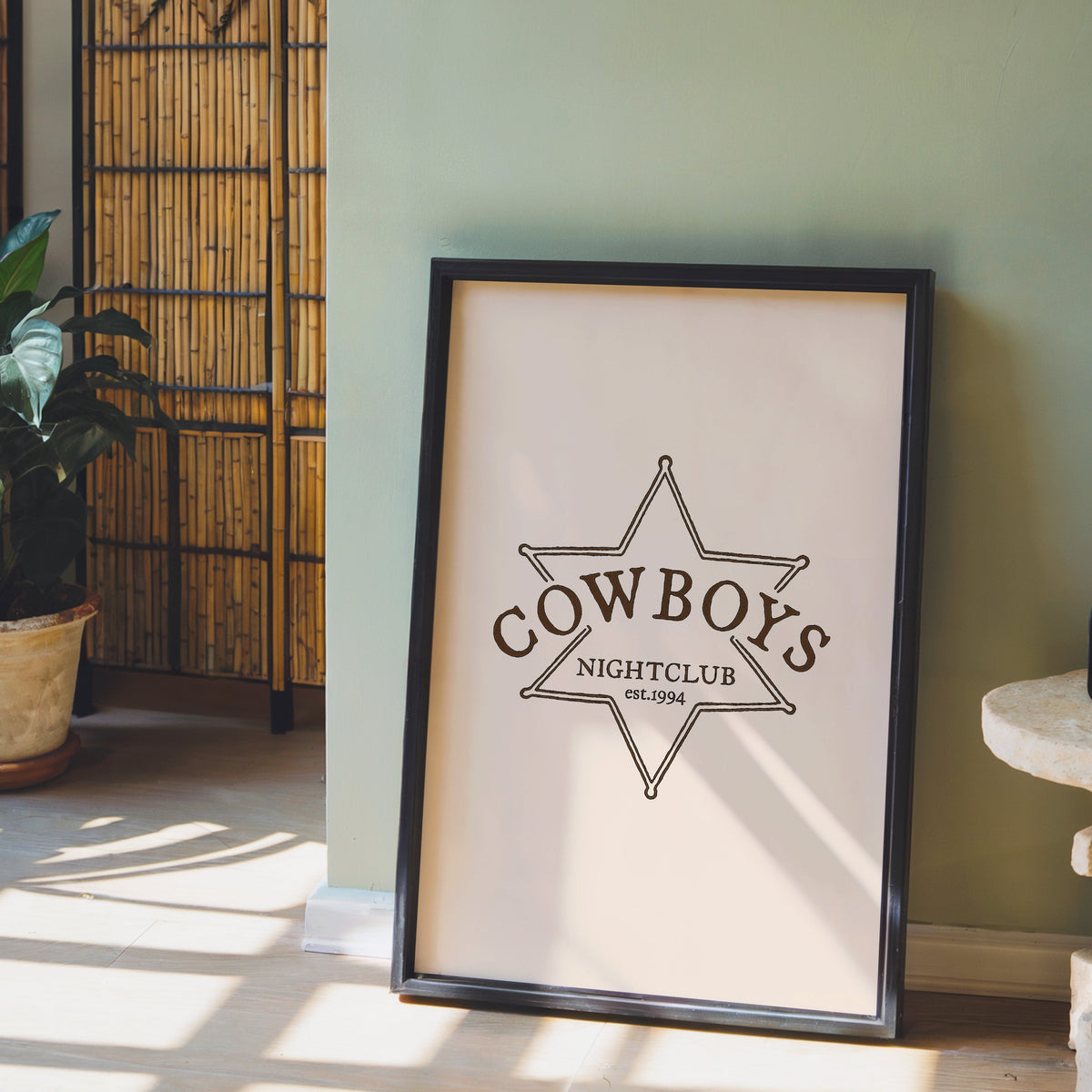 Cowboys Nightclub star print in a black frame leaning against a sage green wall