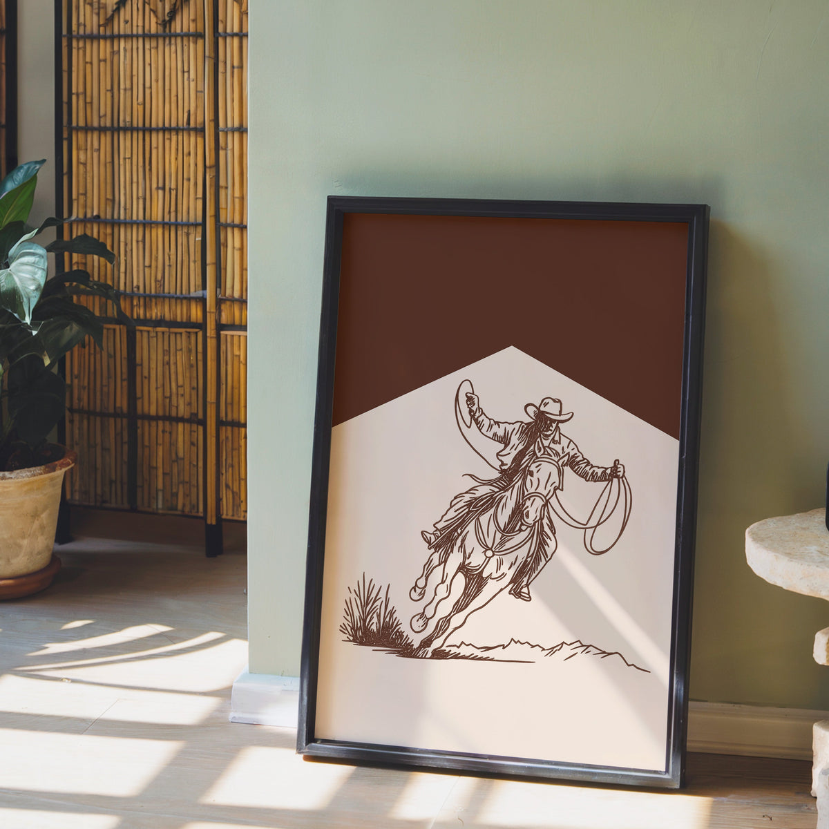 Cowgirl lasso print in a black frame leaning against a sage green wall