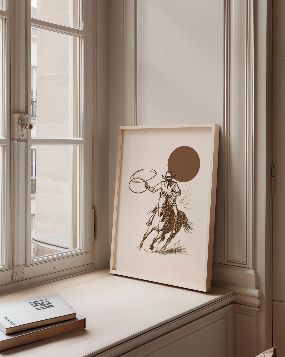 Cowgirl galloping horse print in a pale wood frame on a sunlit window ledge