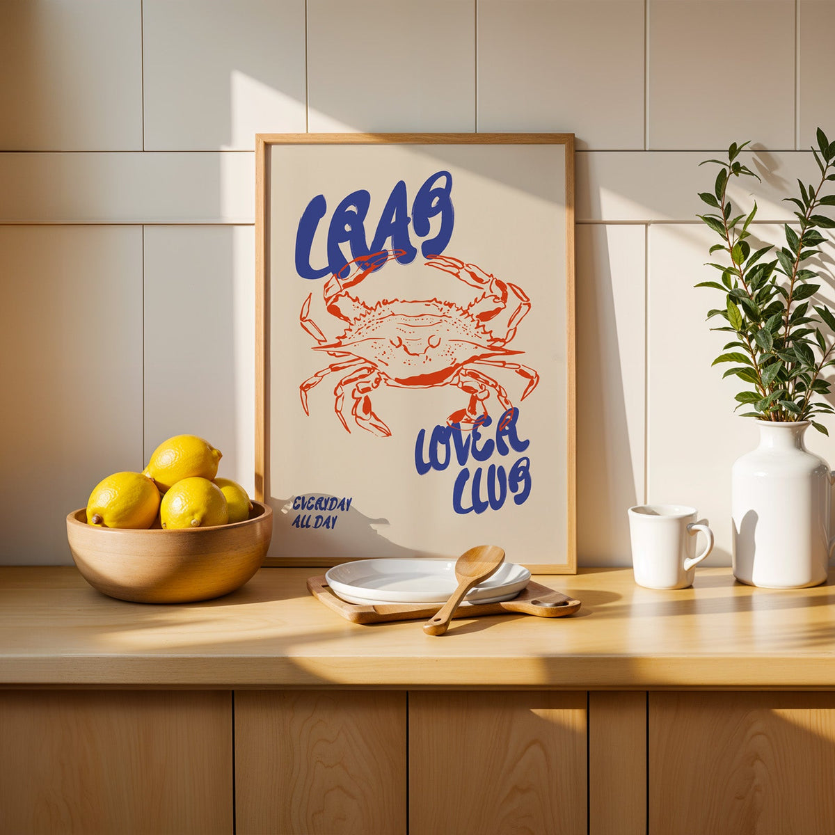 Crab seafood poster in an oak frame on a kitchen counter beside a wooden bowl of lemons