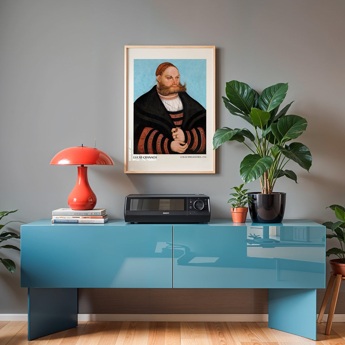 Cranach print in an oak frame above a teal sideboard with a red lamp