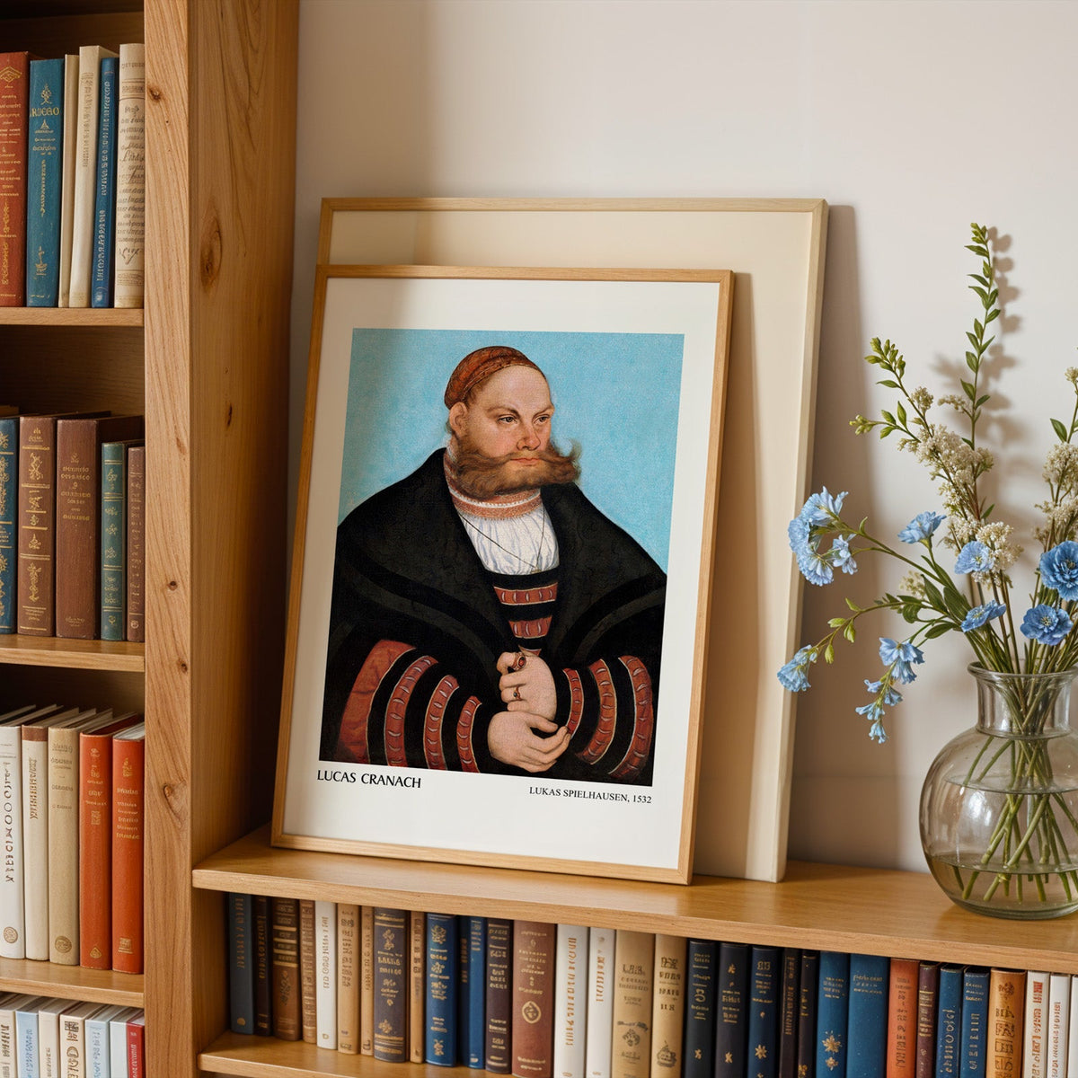 Cranach the Elder print in an oak frame leaning on a bookshelf beside flowers