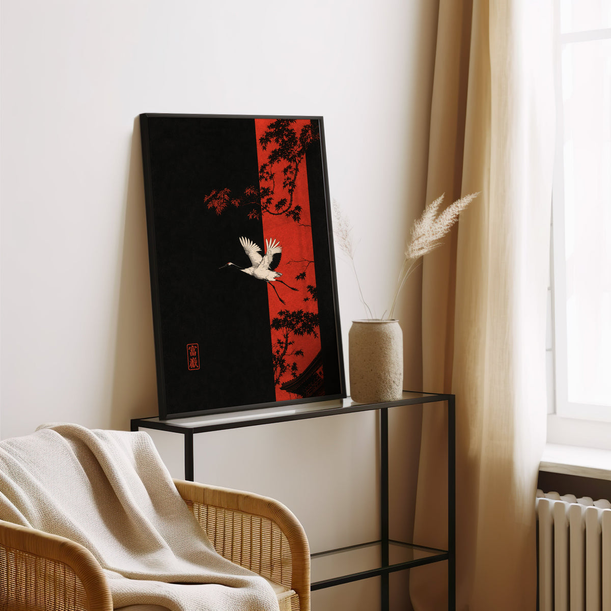 white crane and red maple print in a black frame leaning on a glass console beside pampas grass