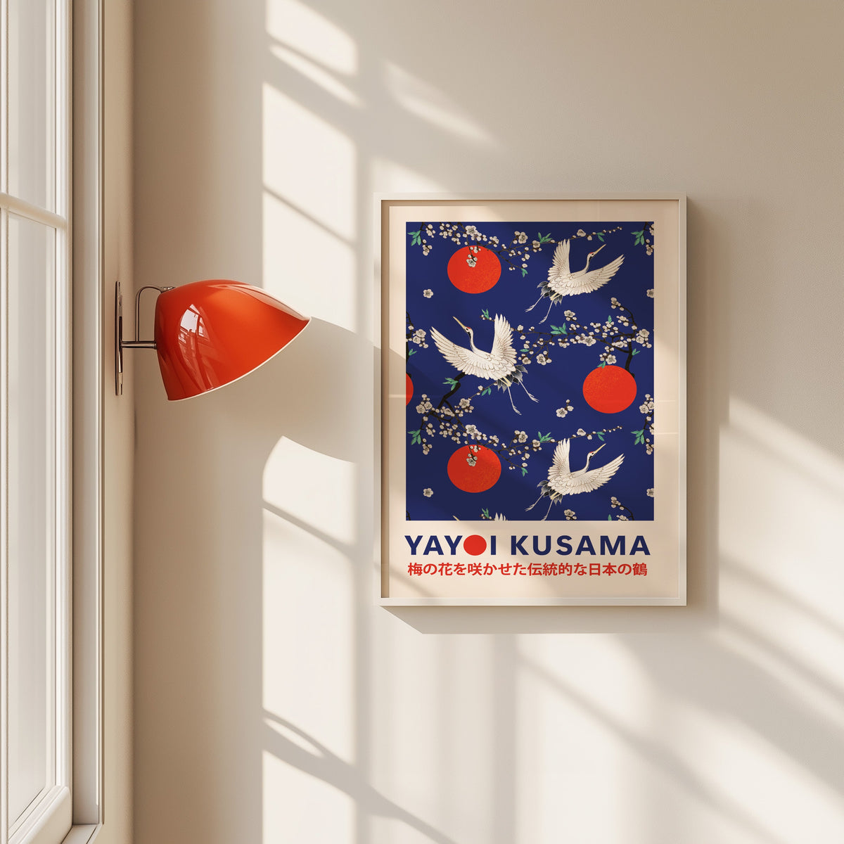 Yayoi Kusama inspired cranes and plum blossom on cobalt print in a white frame beside a red wall sconce