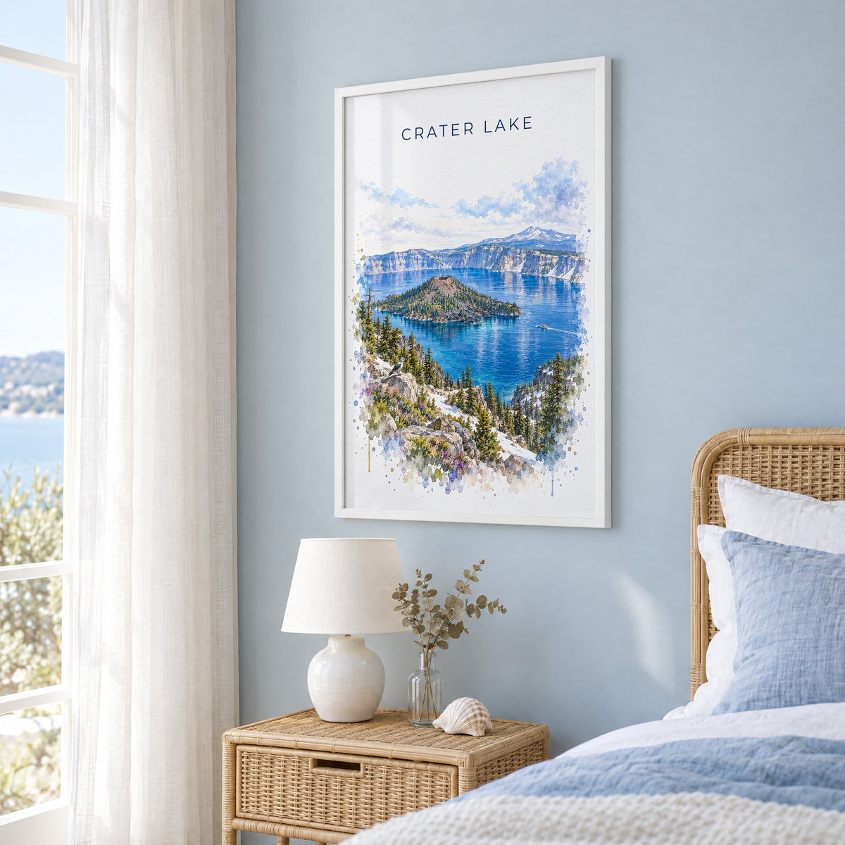 Crater Lake National Park watercolor print in a white frame on a pale blue wall beside a rattan bed in a coastal bedroom