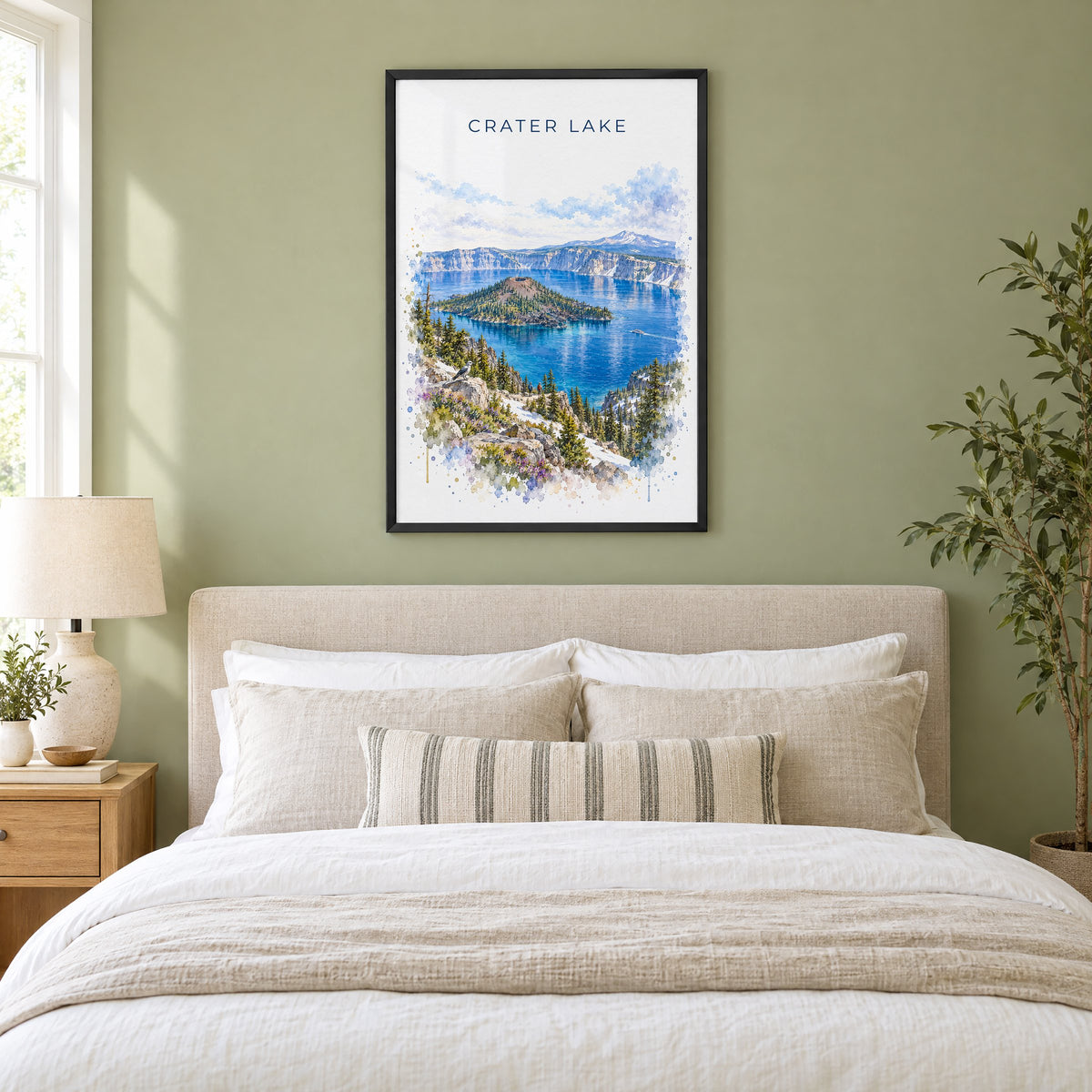 Crater Lake National Park watercolor print in a black frame above an upholstered headboard in a sage green bedroom