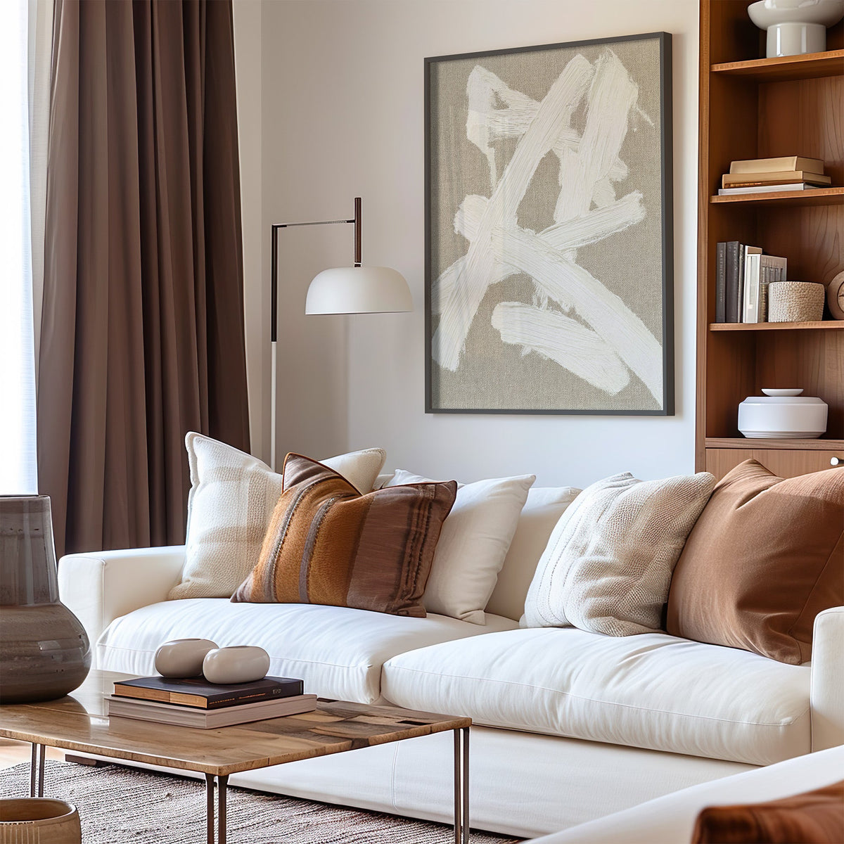 Cream impasto crossed strokes on linen print in a black frame above a cream sofa with brown striped pillows