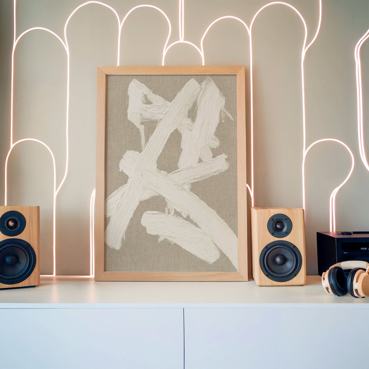 Cream impasto crossed strokes on linen print in a pine frame between wooden speakers by a neon arch light wall