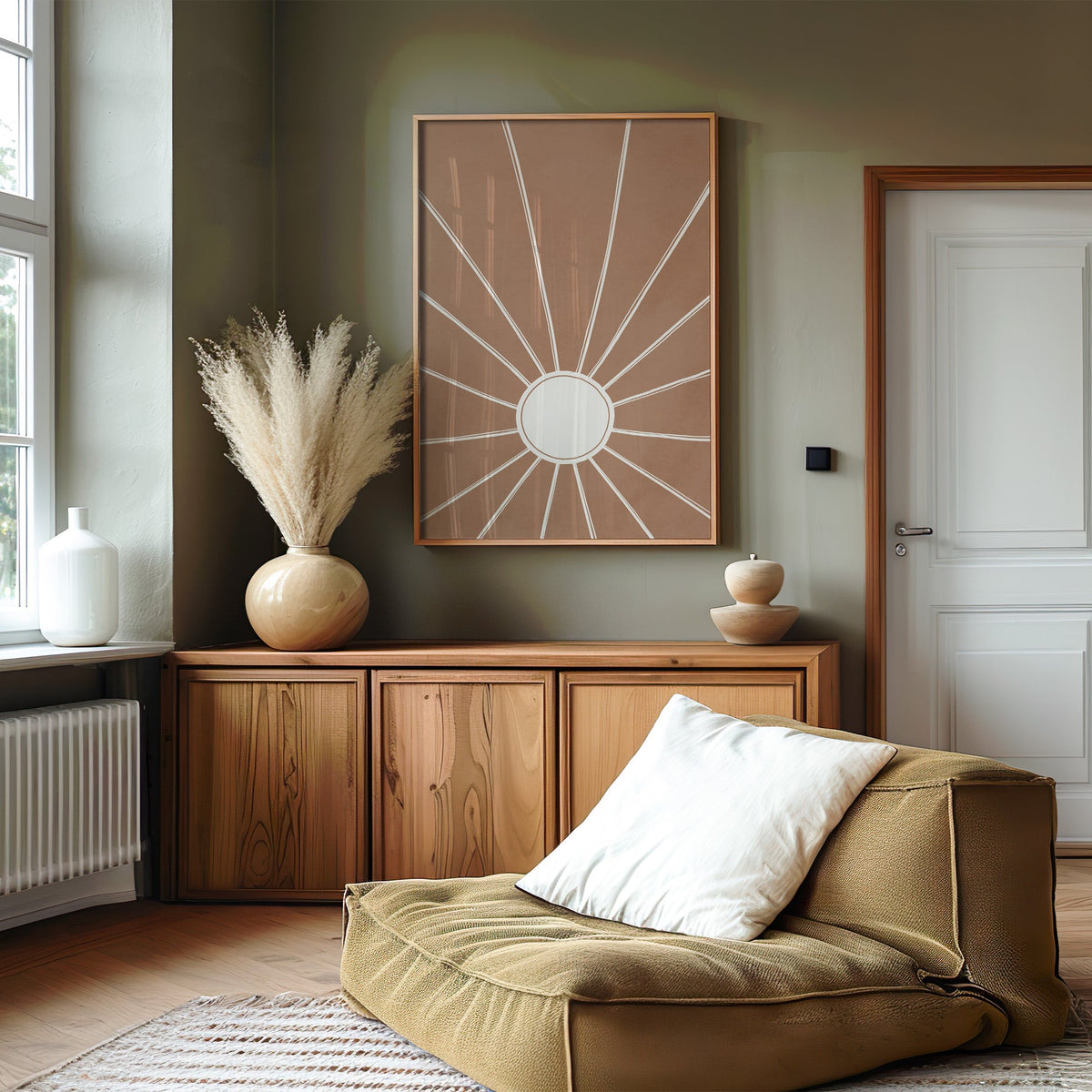 Cream sunburst rays on terracotta boho print in an oak frame on an olive green wall above a wood sideboard with pampas