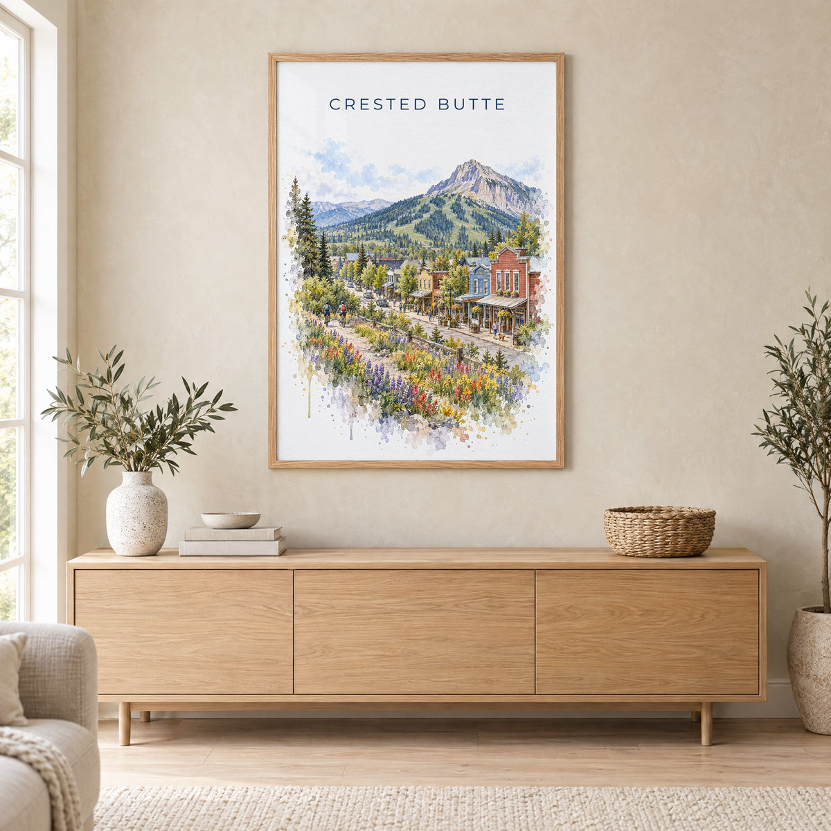Crested Butte watercolor print in an oak frame above a light wood sideboard in a Scandinavian living room