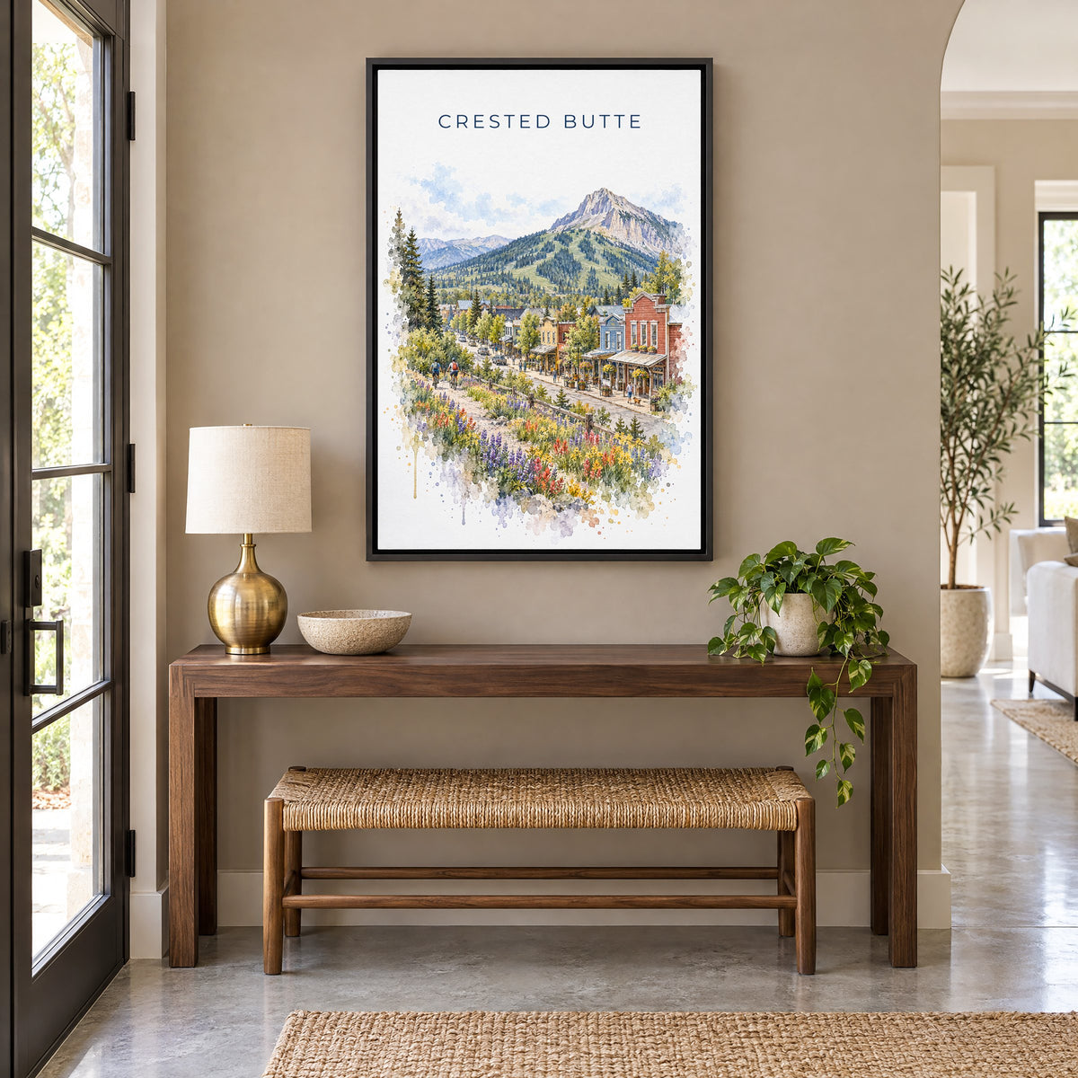 Crested Butte watercolor print as a black floater canvas above a walnut console and woven bench in an entryway