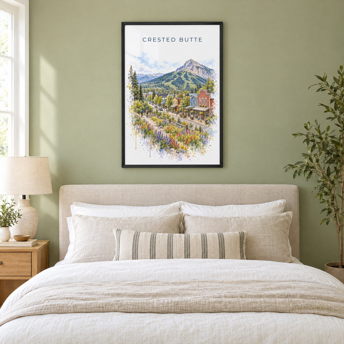 Crested Butte watercolor print in a black frame above an upholstered headboard in a sage green bedroom