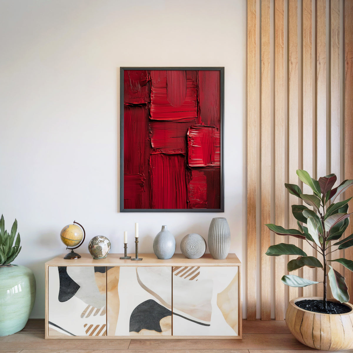 Crimson red impasto blocks abstract print in a black frame above a light wood sideboard by a wood slat wall