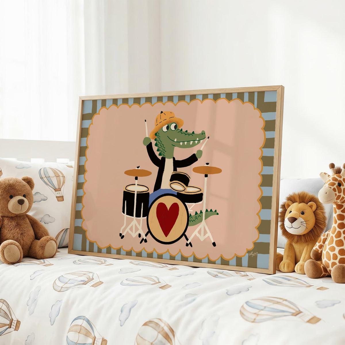 Crocodile playing heart drum kit nursery print in an oak frame on a kids bed with hot air balloon bedding